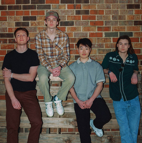 Four members of Shady Trace pose in front of a brick wall